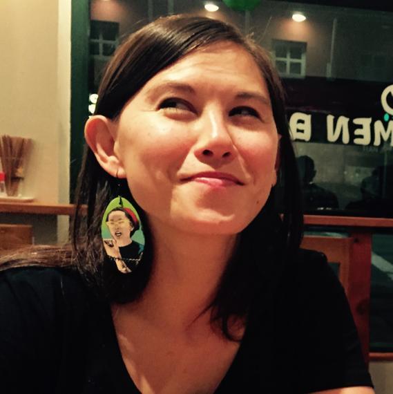 Image description: Jasmin is smiling and looking up. Visible on her right ear is an earring with a drawing of Yuri Kochiyama.