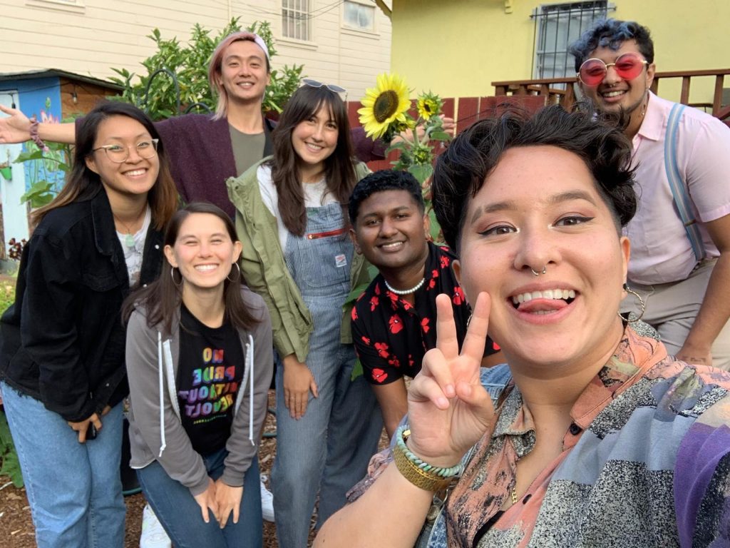 Image description: A group selfie of APIENC staff, a sunflower, and summer organizers smiling outdoors.