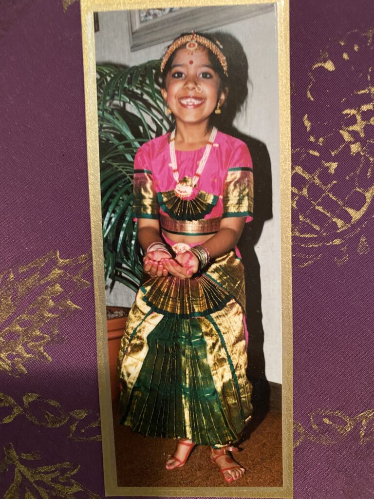 Image description: Meha at 5 years old in a traditional Bharatanatyam dance costume, smiling at the camera.