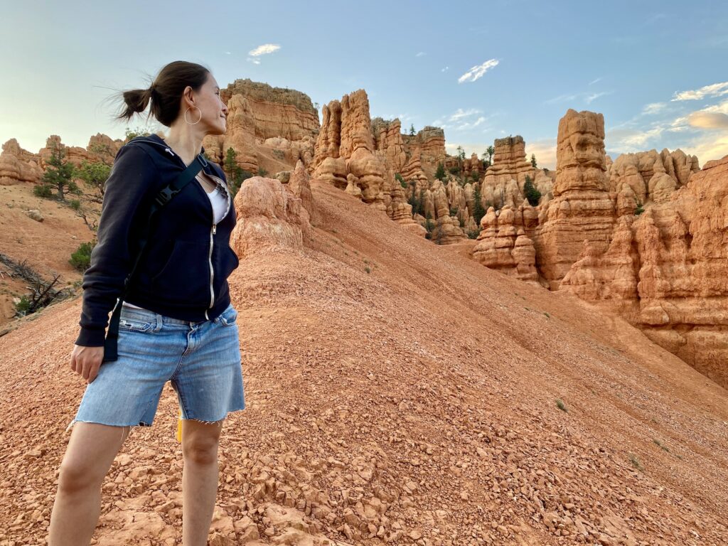 Image description: Photo of Jasmin on her sabbatical road trip, standing on a hill of desert red rocks in Utah, looking off into the distance.