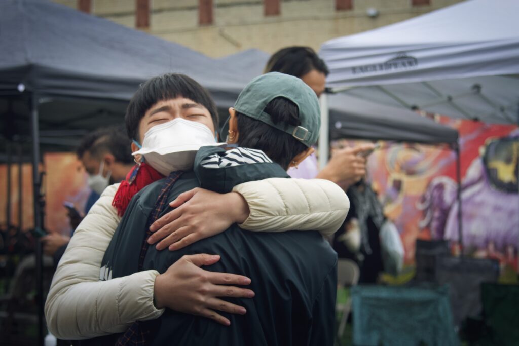 Image description: two LavNix members hold each other & hug.